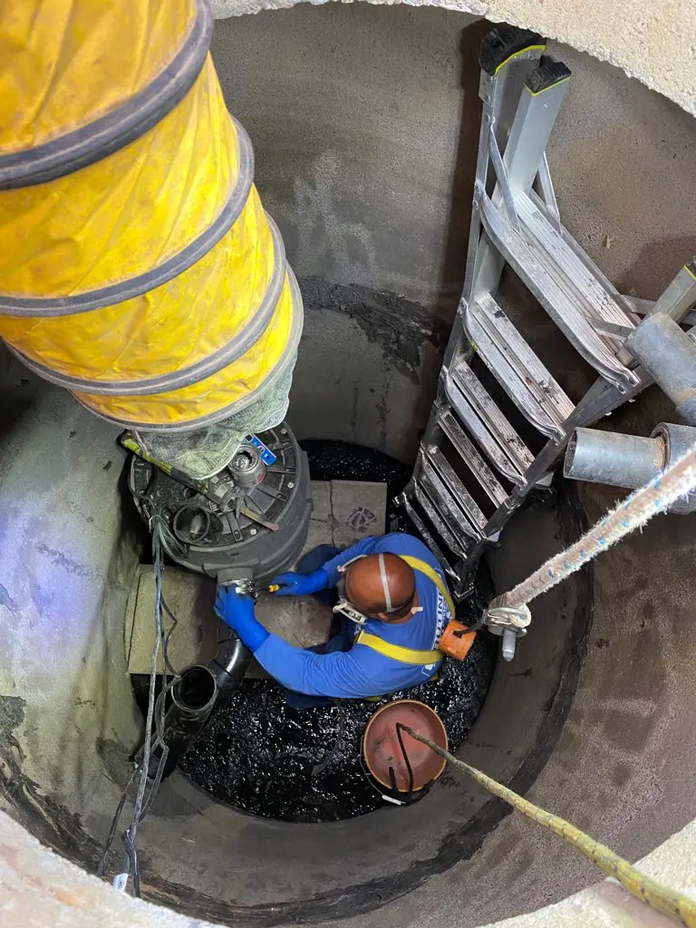 A man in blue shirt standing next to yellow pipe.